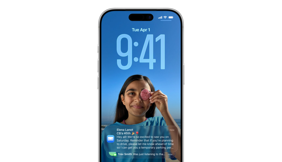 Zamknutá obrazovka iPhonu s fotkou a ?asem vyjád?enym ?íslicemi v Liquid Glass provedení, dole na displeji se objeví dvě oznámení