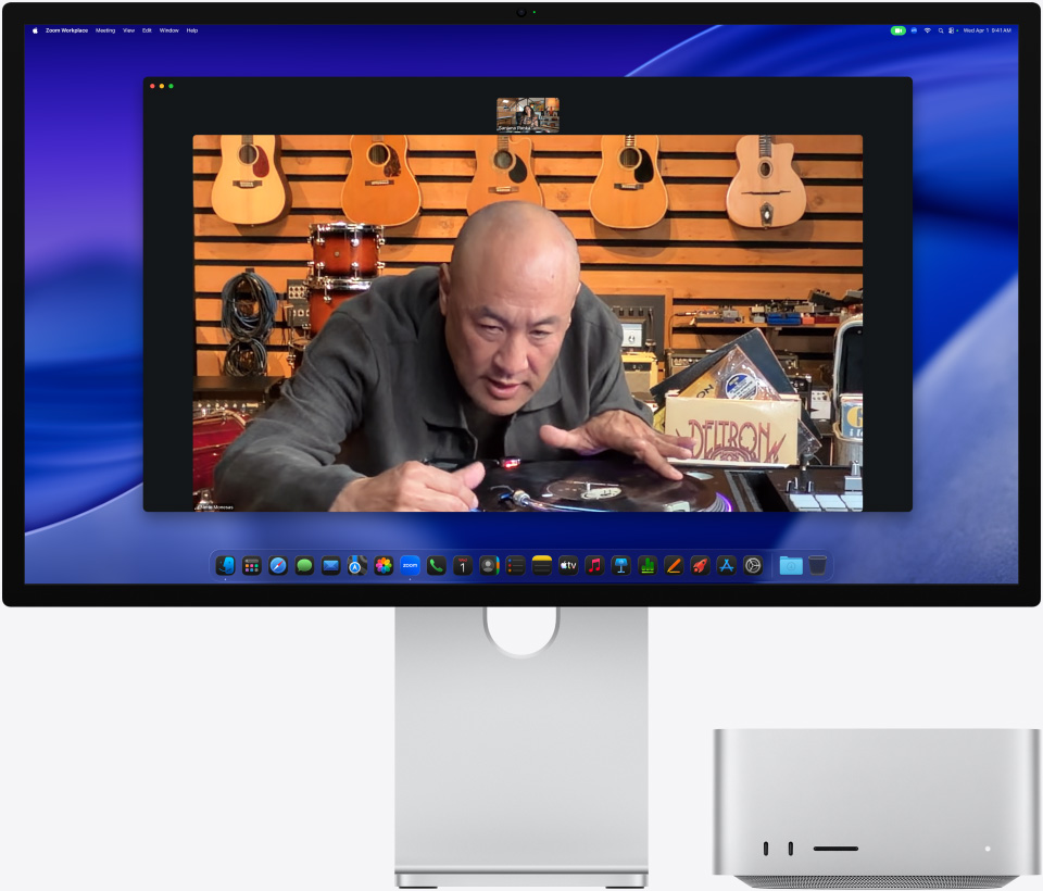 Durante una videochiamata su uno Studio Display XDR con un Mac Studio sotto, una persona in un negozio di strumenti musicali si avvicina a un giradischi