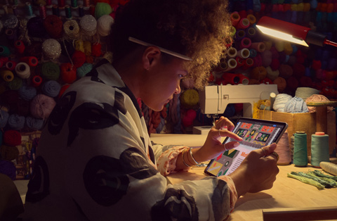 Egy íróa(chǎn)sztalnál ül? ember két ujjával nagyít rá egy képre az iPad kijelz?jén.