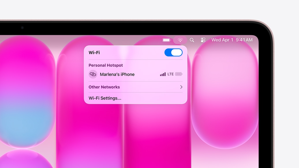 MacBook Neo hajnalpír színben, a Wi-Fi menü Személyes hotspot szakaszában ?Marlena iPhone-ja” látszik választható lehet?ségként.