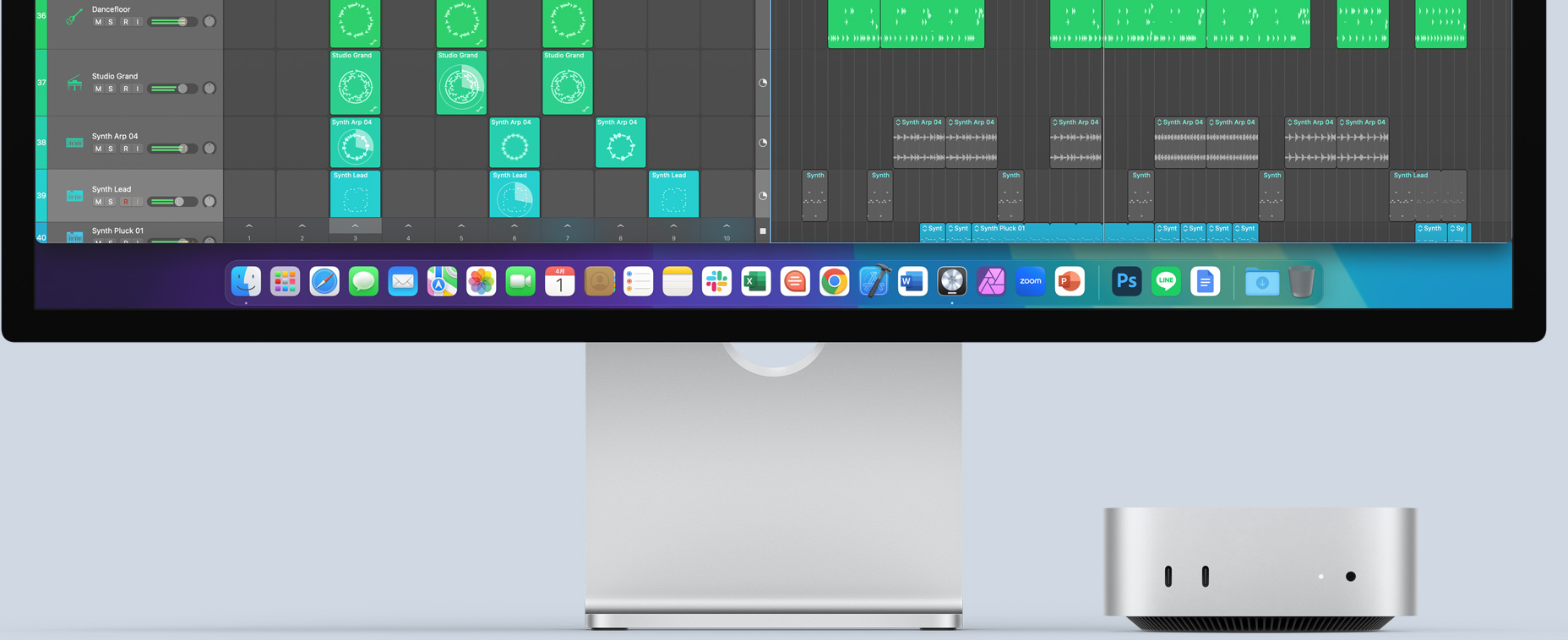 前面のポートとインジケータランプが見えている、シルバーのMac miniの前面。カラフルな畫面と、Dockに様々なアプリのアイコンが表示されたMacのモニタの下に収まっている