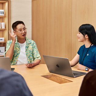 MacBook'u olan bir Apple Store ?al??an?, bir ki?iyle etkile?ime giriyor.