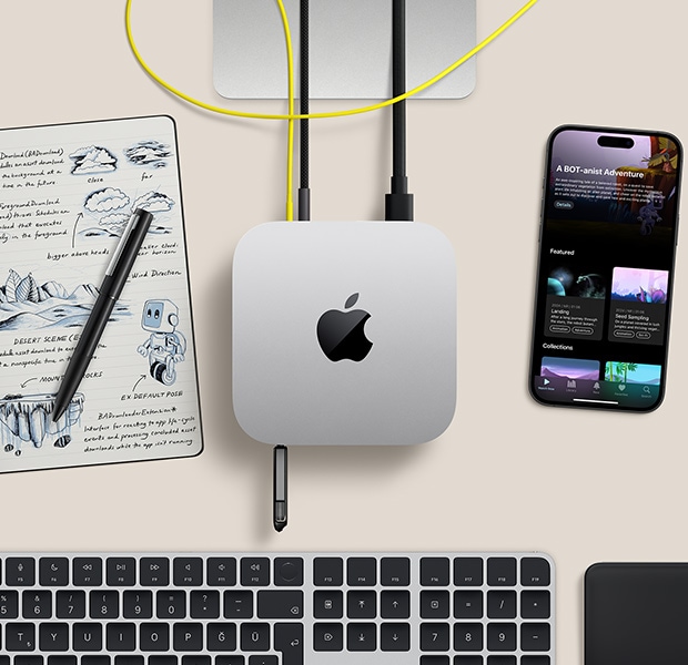 Ba?lant? noktalar?na bir flash bellek ile kablolar?n ba?l? oldu?u gümü? rengi Mac mini ile kablosuz klavye, trackpad, iPhone ve bir not defterinin bulundu?u masa düzeninin üstten g?rünümü