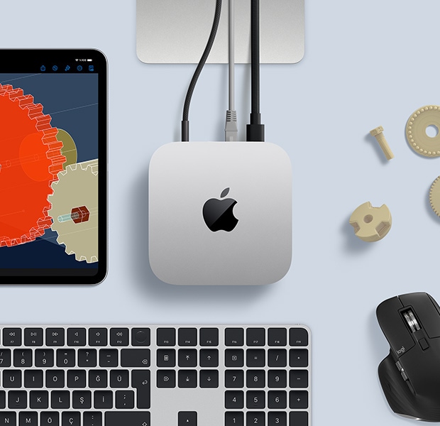 Gümü? rengi Mac mini, siyah ve gümü? rengi kablosuz klavye, siyah bir mouse ve bir iPad’in bulundu?u masa düzeninin üstten g?rünümü
