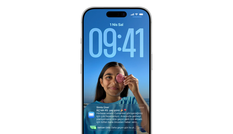 iPhone Kilit Ekran?’nda bir foto?raf, Liquid Glass efektiyle saat rakamlar?, ekran?n alt?nda iki bildirim g?rünüyor