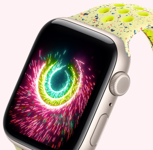 Apple Watch SE 3 med urkasse av aluminium i stjerneskinn og Nike Sport Band i Volt Splash viser fyrverkerilignende aktivitetsringer p? skjermen.