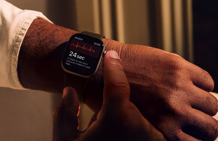 Cilvēks tur nospiestu Apple Watch Series 11 Digital Crown, lai EKG aplikācijā izmērītu sirds veselības rādītājus