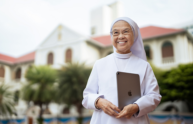 Headmistress Sister Fran?oise Jiranonda stands outside the school holding her iPad.