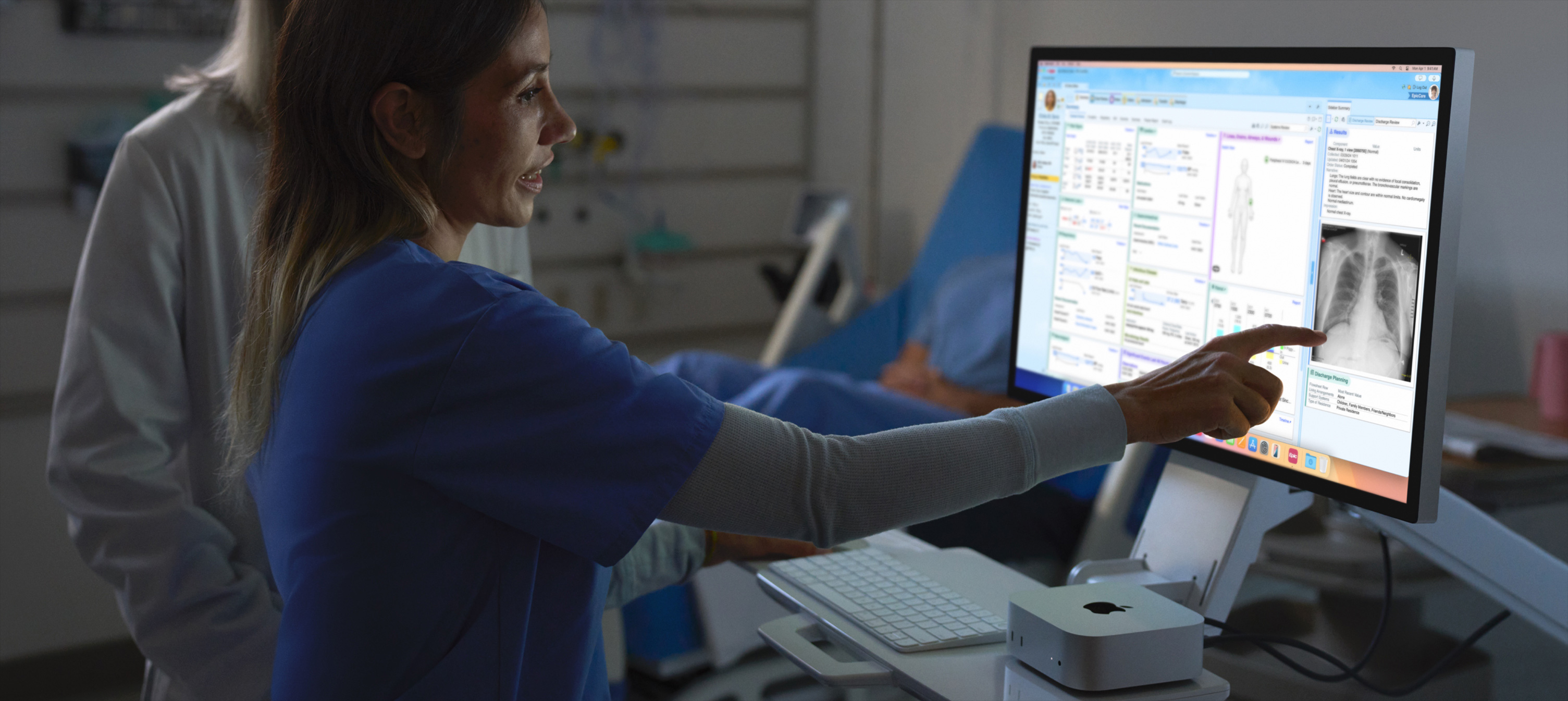 Et billede af en sygeplejerske, der peger p? en patients r?ntgenbillede p? en iMac.