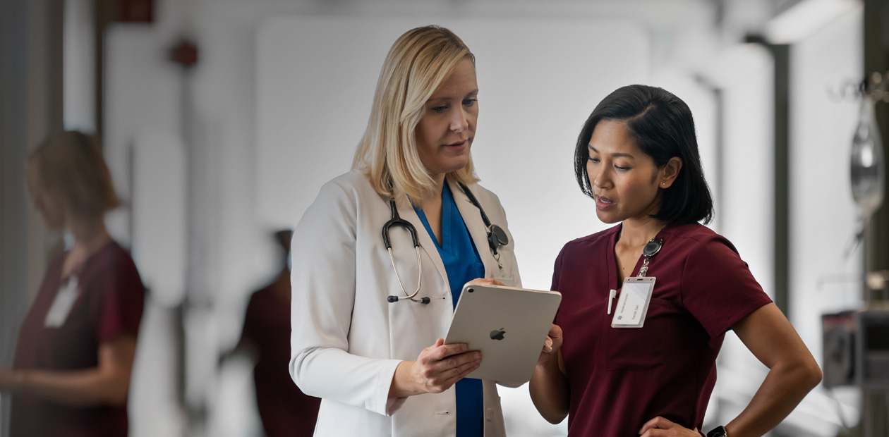 En l?ge og en sygeplejerske st?r p? en hospitalsgang og kigger sammen p? en iPad.