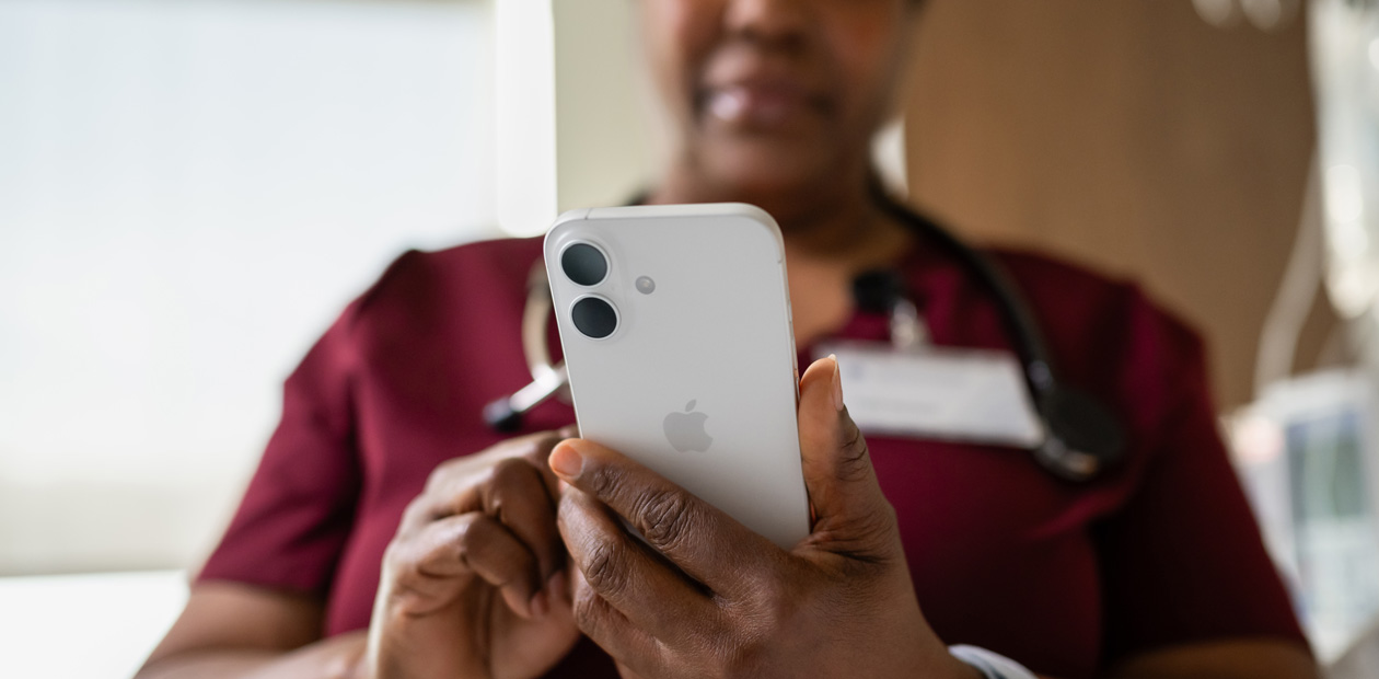赤いスクラブを著た女性看護師がiPhoneを見ている