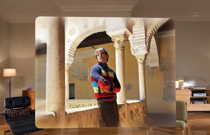 Scène spatiale montrant la photo d’un homme appuyé contre le balcon d’une cour sinueuse, avec de la profondeur et du relief dans le cadre