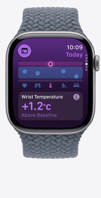 Apple Watch Series 11 z tytanow? kopert? w kolorze ?upku i plecion? opask? Solo w kolorze marynarskiego granatu. Na ekranie apka Parametry ?yciowe pokazuje wykres przedstawiaj?cy stan zdrowia i powiadomienie o temperaturze nadgarstka powy?ej warto?ci bazowej. Na prawym boku urz?dzenia pokr?t?o Digital Crown.