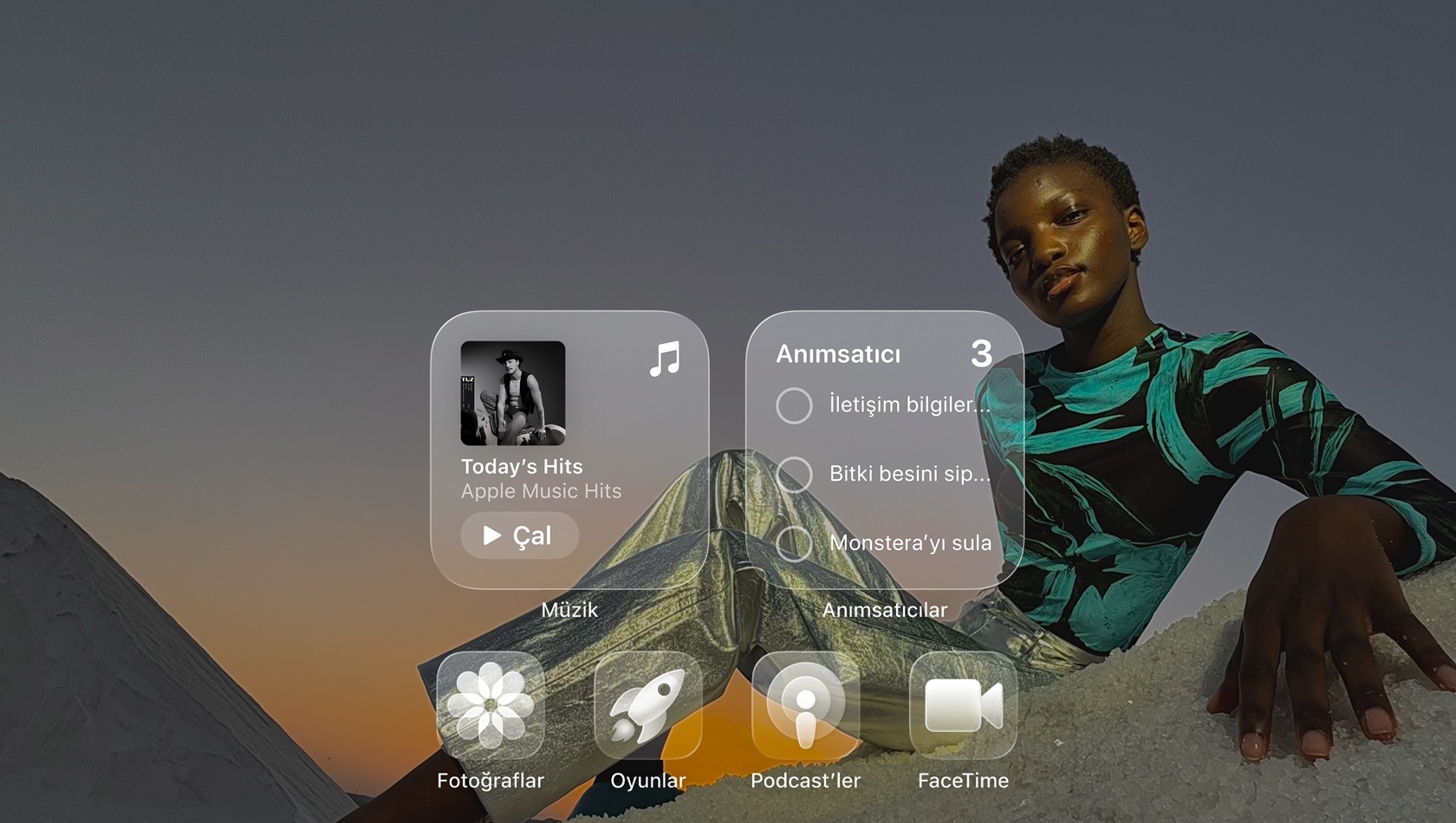 Liquid Glass ekrandaki Apple Music, An?msat?c?lar, Foto?raflar, Oyunlar, Podcast’ler ve FaceTime gibi ?effaf uygulama simgeleri duvar ka??d?n? yans?t?yor