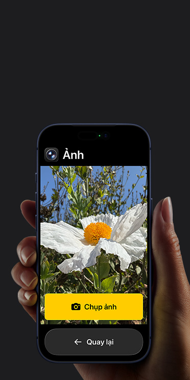 Màn hình iPhone 17 Pro hi?n th? giao di?n ?ng d?ng Camera gi?n l??c v?i b?ng hoa tr?ng trong khung hình, nút “Ch?p ?nh” và nút “Quay l?i” bên d??i